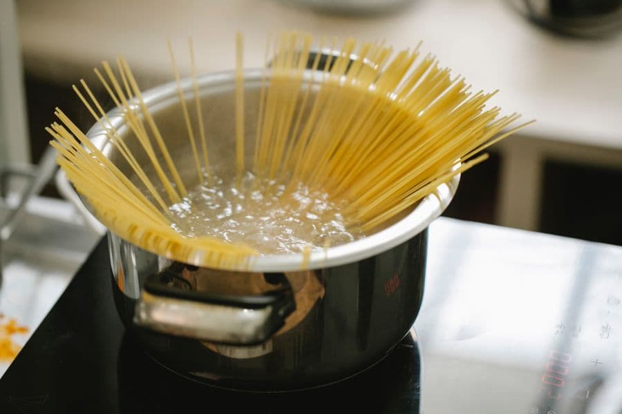 Spaghetti fanned into a pot of boiling water on an induction hob